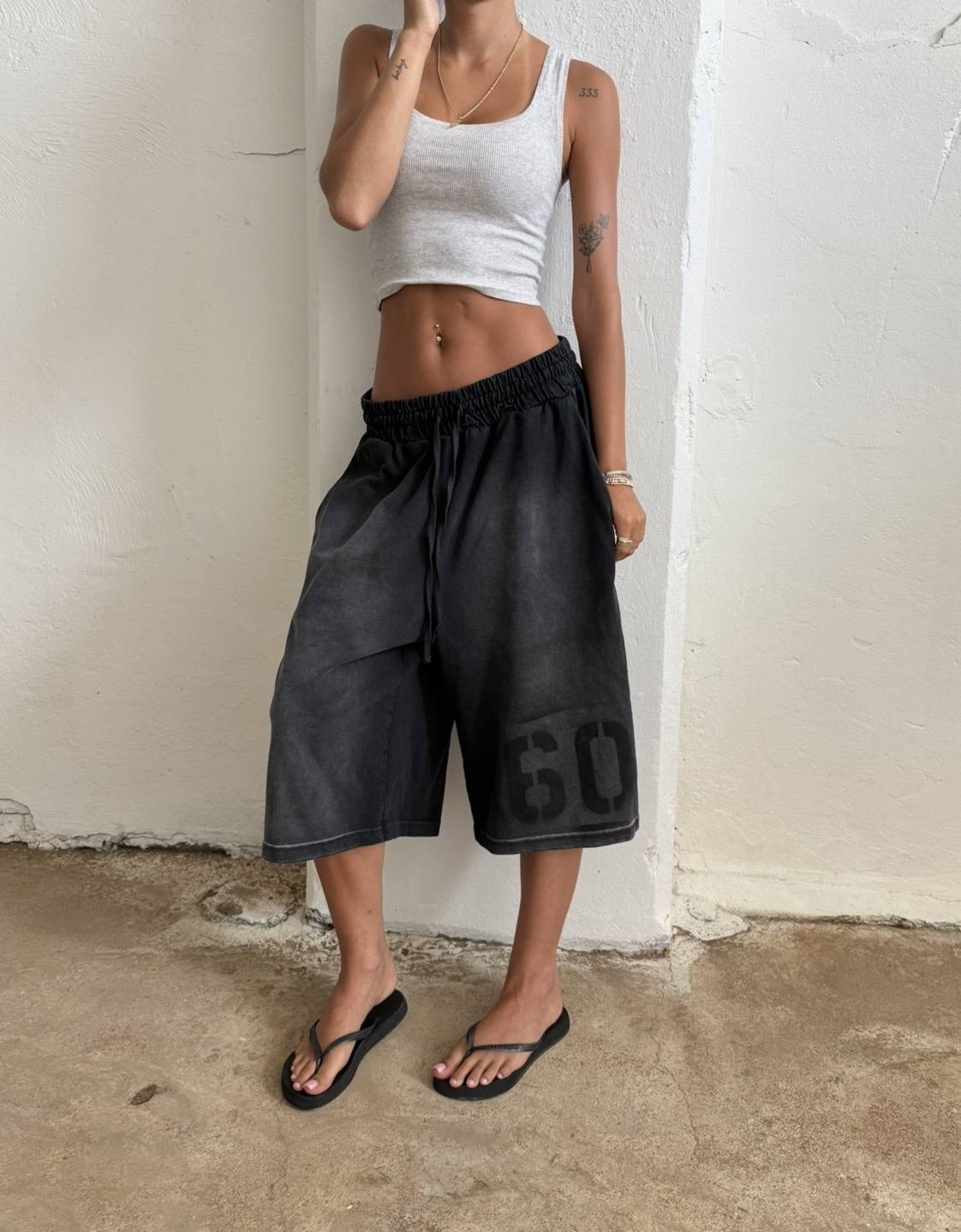Made In LA Shorts worn with a grey tank against a white stucco wall
